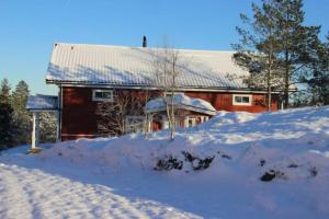 Bäckefors的住宿－Lillesjö stuguthyrning，前面的红谷仓,地上有雪