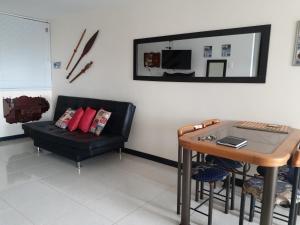 ein Wohnzimmer mit einem schwarzen Sofa und einem Tisch in der Unterkunft construcciones Guaduales del café in Montenegro