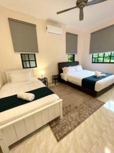 a bedroom with two beds and two windows at Villa Ruby - with private swimming pool in Kota Bharu
