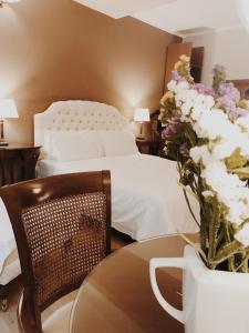 Un dormitorio con una cama y una mesa con un jarrón de flores en Five Seasons Pension, en Nauplia