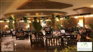 a dining room with tables and chairs and plants at فندق بردى in Qaryat al Bulush