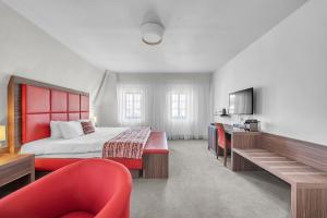 a hotel room with a bed and a red chair at Hotel Nelly Kellys in Trutnov +71 photos
