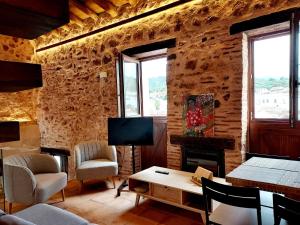 a living room with a table and chairs and a tv at Balcón de la Moreria con alberca in Constantina