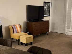 ein Wohnzimmer mit einem TV, einem Stuhl und einer Kommode in der Unterkunft Large Creekside Studio at Shadow Mountain Resort and Club in Palm Desert