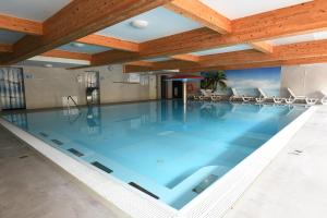 a large swimming pool in a building with a wooden ceiling at Ośrodek Chrobry in Pokrzywna