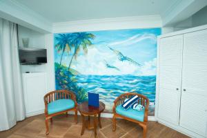 ein Zimmer mit 2 Stühlen und einem Gemälde des Ozeans in der Unterkunft Samfi Gardens in Soufrière