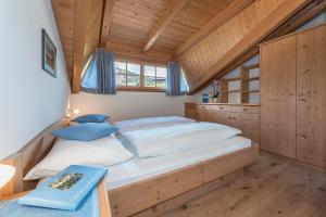 Cama grande en habitación con techo de madera en Bergblick App Lärche en Funes