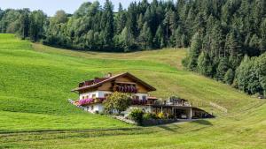 uma casa no meio de um campo verde em Bergblick App Lärche em Funes