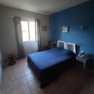 a blue bedroom with a bed and a window at Villa U Puntale in Ghisonaccia