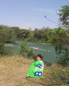 a young girl holding a kite next to a river at Hotel Fazenda Aldeia do Vale in Jacareí