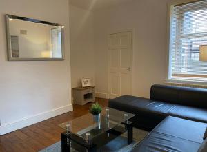 a living room with a black leather couch and a table at Alexander Apartments Gateshead North in Gateshead