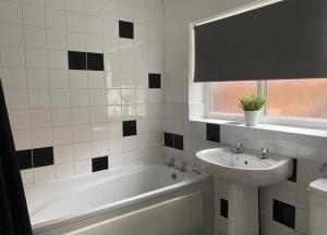 un bagno bianco con lavandino, vasca e lavandino di Alexander Apartments Gateshead North a Gateshead