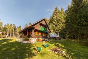 a log cabin with two chairs in the grass at Chalet Trzinka - Triglav National Park in Goreljek