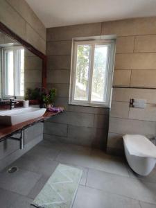 a bathroom with two sinks and a toilet and a window at Dehradun Beautiful new private cottage with Kitchen in the Hills in Dehradun
