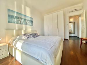 een witte slaapkamer met een groot bed en een houten vloer bij CASAVIVA - Bilo with SeaView and parking in Camogli in Camogli