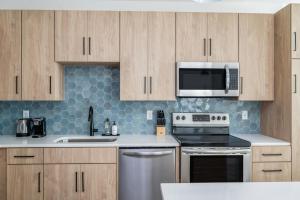 a kitchen with stainless steel appliances and wooden cabinets at Kasa Bryn Mawr Minneapolis in Minneapolis