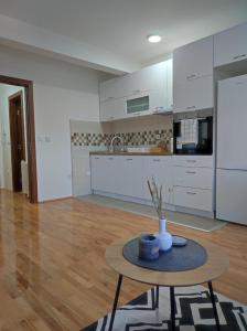 una cocina con armarios blancos y una mesa en una habitación en SP Apartmani FREE PARKING en Vranje