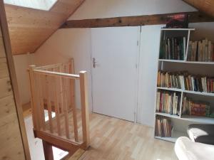 a room with a staircase and a book shelf with books at Grand gite 14 personnes ,cour ,salle de jeux, proche du village , commerces in Murat