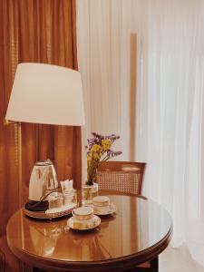 a table with a lamp and plates and flowers on it at Five Seasons Pension in Nafplio