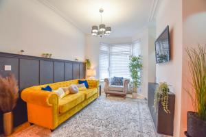 ein Wohnzimmer mit einem gelben Sofa und einem Stuhl in der Unterkunft Modernistic 4-bedroom home close to City Centre in Cardiff