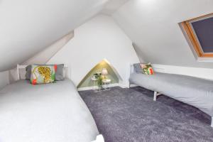 um quarto no sótão com 2 camas e uma janela em Modernistic 4-bedroom home close to City Centre em Cardiff