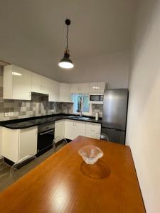 Una cocina con una mesa de madera y una cocina con gabinetes blancos. en Primero el Wiro, en Puerto