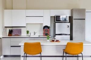 una cocina con armarios blancos y 2 sillas naranjas en Suite Retreat at The Lofts en Kingston