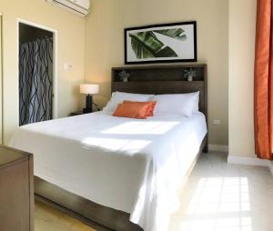1 dormitorio con 1 cama blanca grande con almohada naranja en Suite Retreat at The Lofts, en Kingston