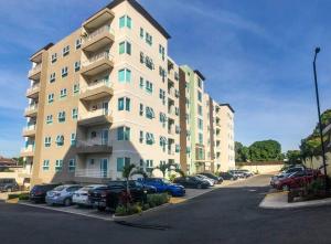 um grande edifício de apartamentos com carros estacionados num parque de estacionamento em Suite Retreat at The Lofts em Kingston
