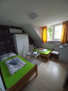 een slaapkamer met een groen bed en een tafel en stoelen bij Fekete Macska Panzió in Tata