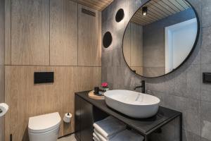 La salle de bains est pourvue d'un lavabo et d'un miroir. dans l'établissement Apartamenty z widokiem na morze i dziedziniec, parking BalticON Morska 6, à Kołobrzeg