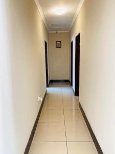 an empty hallway with white walls and a tile floor at Airport Royal Guest House in Kempton Park