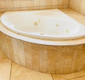 a bath tub in a bathroom with a wooden floor at Airport Royal Guest House in Kempton Park