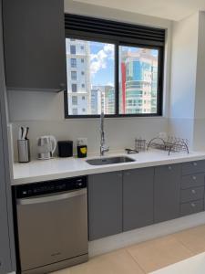 a kitchen with a sink and a window at Apartamento Frente Mar com vista praia em Itapema in Itapema