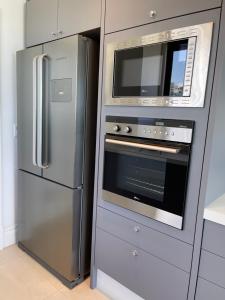 a kitchen with a stainless steel refrigerator and a microwave at Apartamento Frente Mar com vista praia em Itapema in Itapema