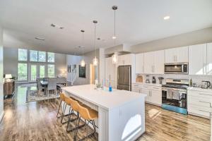 a kitchen with white cabinets and a kitchen island with bar chairs at Modern Houston Gem about Walk to Minute Maid Park in Houston