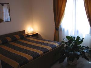 a bed in a room with a window and a plant at Hotel Su Giudeu in Chia