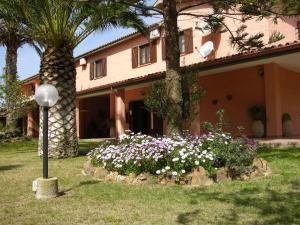 a house with a bunch of flowers in the yard at Hotel Su Giudeu in Chia