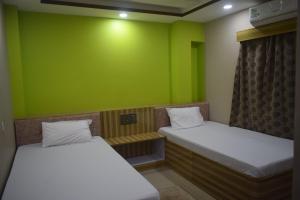 two beds in a room with a green wall at Airport Lodge in Siliguri