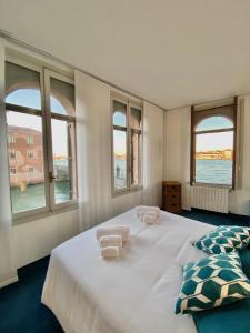 sypialnia z dużym białym łóżkiem i oknami w obiekcie Al Ponte Lungo - Giudecca w Wenecji