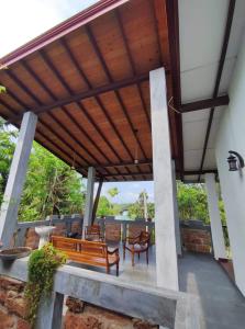 a patio with a bench and chairs under awning at Sanuki Villa in Hikkaduwa
