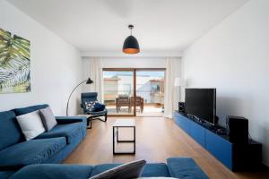 a living room with a blue couch and a tv at Terraços do Rio by CORAL in Portimão