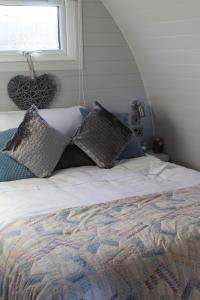 a bedroom with a bed with pillows and a window at The Pod - Luxury Glamping Holiday Lodge in Arley