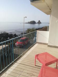 einen Balkon mit einem roten Tisch und Meerblick in der Unterkunft APPARTAMENTO FRONTE MARE ACi TREZZA in Aci Castello