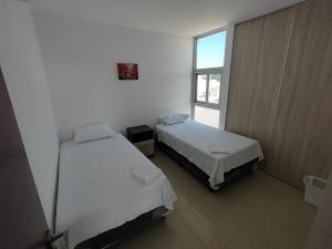 two beds in a small room with a window at Edificio Atlantis Tower, Confortable y Agradable in Santa Cruz de la Sierra