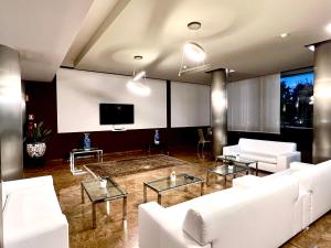 sala de estar con muebles blancos y TV de pantalla plana en Hotel & Residence Castelli, en Montecchio Maggiore