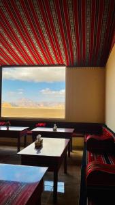 a room with two tables and a large window at Ammar Rum Camp and jeep tour in Wadi Rum