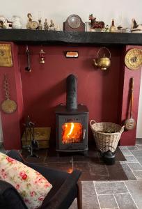 a wood stove in a room with a red wall at Tosses Cottage - Secluded cottage with hot tub in Newry