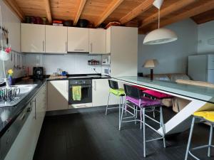 a kitchen with white cabinets and a counter with stools at Casa dos Biscoitos in Praia da Vitória