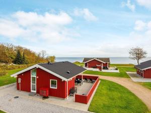 ein rotes Haus mit einer Terrasse vor dem Meer in der Unterkunft Holiday home Sydals LXXI in Mommark